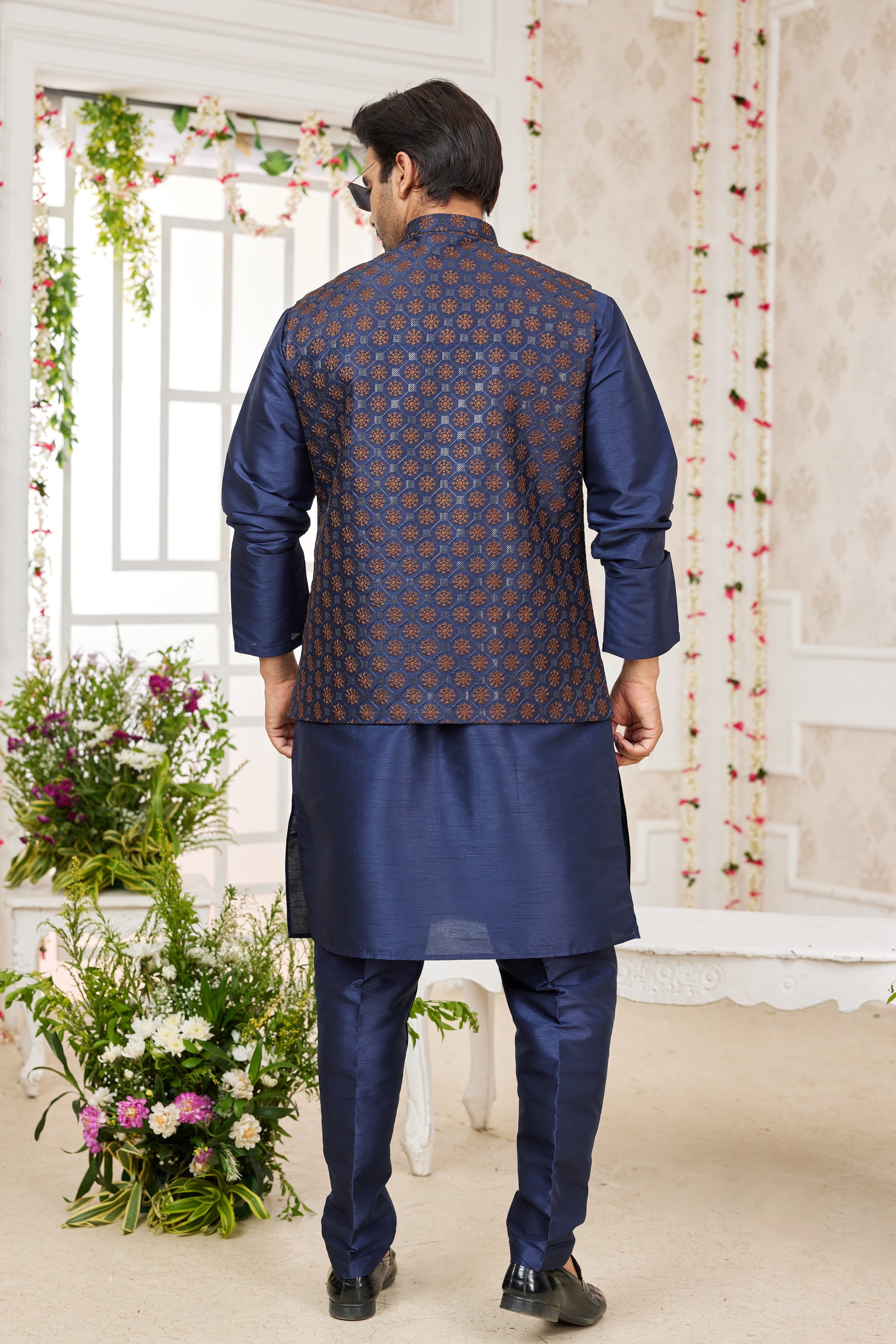 Man wearing a blue kurta with a patterned shirt in a decorated room.
